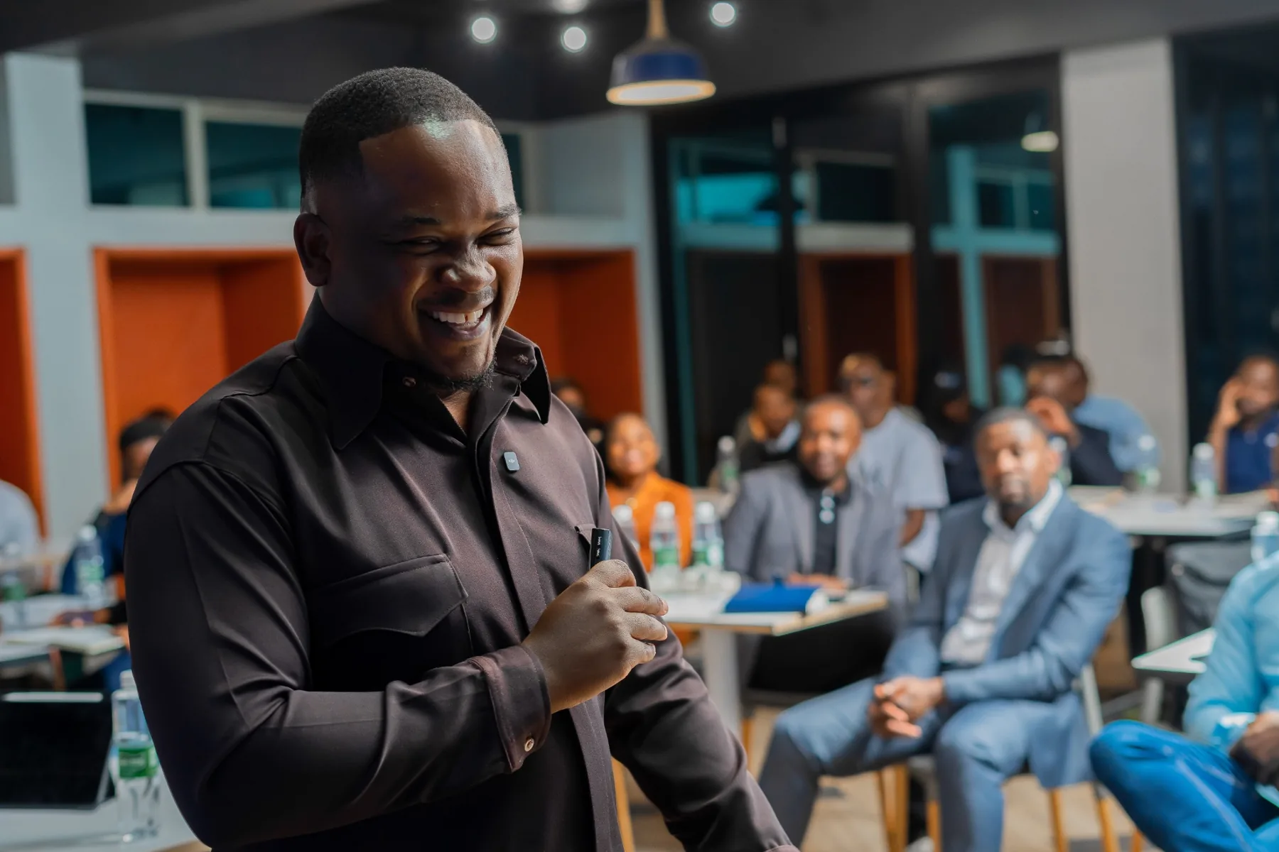 Brian Munyawarara smiling during a Founder Friday session with attendees seated behind him